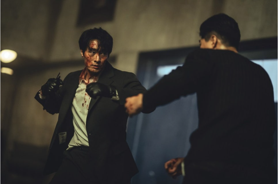 격투기 선수와 치열하게 싸우고 있는 남기준. 많은 싸움으로 지쳐 있는 남기준의 모습.