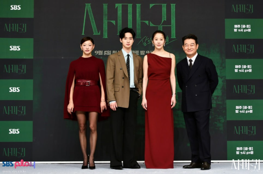 SBS 드라마 '사마귀'의 출연 배우 4명이 포즈를 취하고 있습니다. 배우들은 어두운 배경과 대조되는 버건디/레드 계열 드레스와 정장을 입고 있습니다. 드라마의 방영 정보('매주 [금,토] 밤 9시 50분')와 제목('사마귀')도 배경에 보입니다.