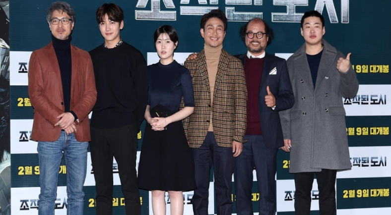 영화 **'조작된 도시'**의 주연 배우들과 감독이 개봉 전 홍보 행사에 참여해 기념 촬영을 하는 모습입니다.