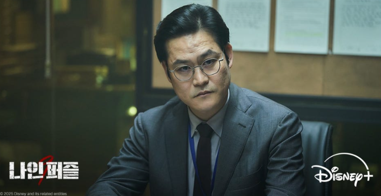 디즈니+ 오리지널 시리즈 '나인 퍼즐' 속 인물의 차갑고 예리한 면모를 포착한 장면입니다.