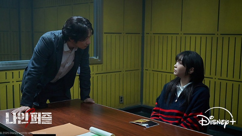디즈니+ 오리지널 시리즈 '나인 퍼즐' 속 두 인물의 팽팽한 대립을 담은 취조실 장면입니다.